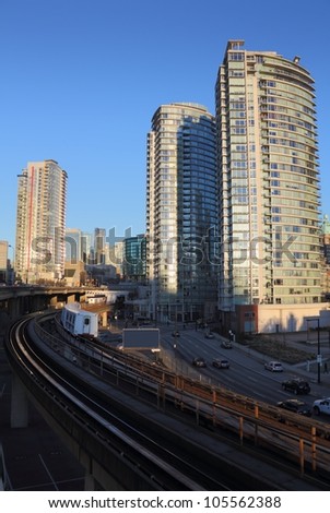 Downtown Vancouver, Commuter Rail. Vancouver condominiums and office towers in the morning sun. A commuter train pulls into a station. British Columbia, Canada.