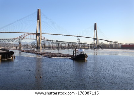 Fraser River Winter Log Boom. Tugboats maneuver a log boom under three bridges crossing the Fraser River in New Westminster, British Columbia, Canada.
