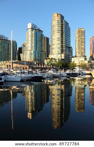 Coal Harbor Condominiums reflect the early morning light in the calm water of the marina across from them. Vancouver, British Columbia, Canada.