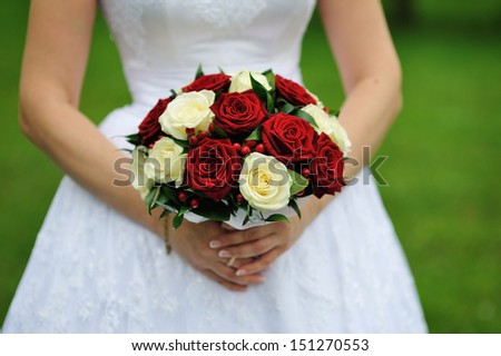 Bride holding wedding flower bouquet of red and white roses