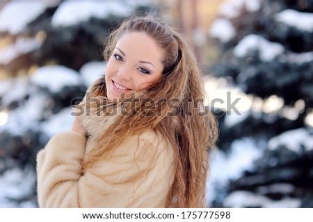 beautiful girl on the street near fir-tree in winter.