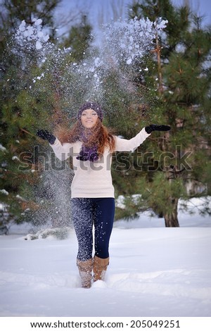beautiful girl in winter snow throws hands