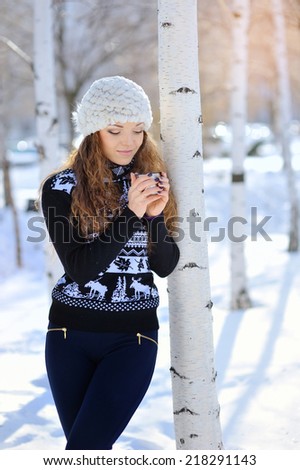 Outdoor portrait of beautiful woman in winter holding a cup with hot drink