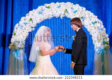 bride and groom in the arch wear wedding rings