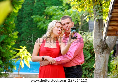 Couple fun taking self-portrait picture photos with mobile smart phone or pocket camera outdoors. Happy multiracial young couple in love taking pictures together on summer vacation. Man and woman.