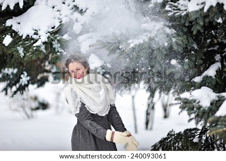 beautiful woman in winter knitted mittens throws snow.