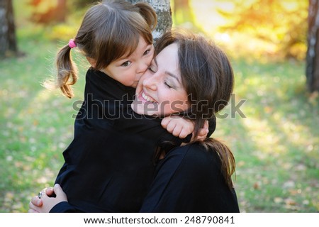 daughter kissing her mother in the park.