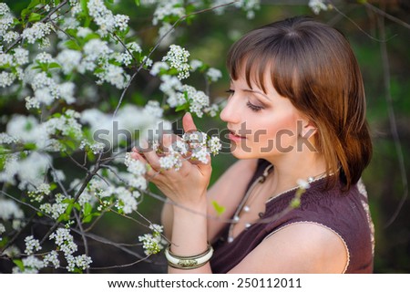beautiful woman is smelling white flowers in spring park.