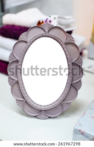 Small round mirror in a frame is on the table
