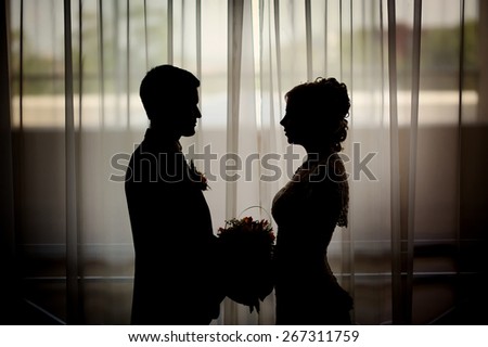 Silhouette of a bride and groom on the background of a window.