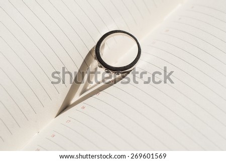 wedding ring is on the page diary and makes a shadow in the form of heart.
