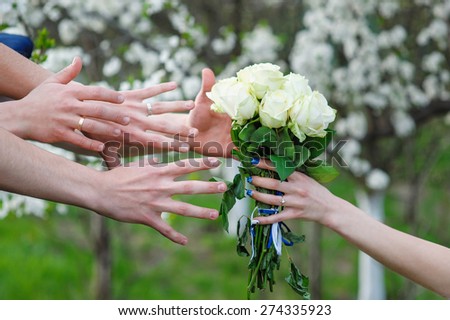 bride holds a wedding bouquet and hands reaching for him.