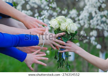 bride holds a wedding bouquet and many hands reach for him.