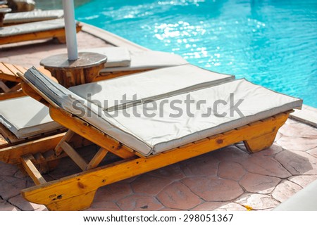 Wooden bed beside the pool. The beds are arranged behind the pool\'s edge.