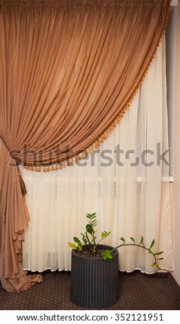 Part of beautifully draped curtain and wall with patterns.