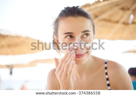 beautiful woman smears face sunscreen at the beach for protection.