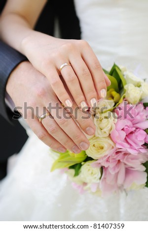 Hands and rings on wedding bouquet