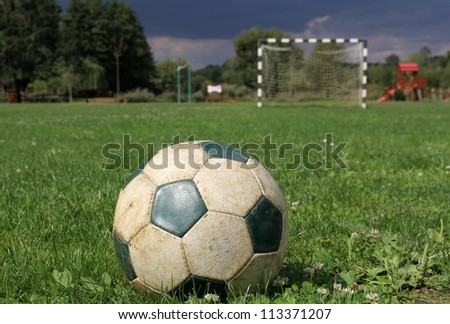 A leather soccer ball with a goal at the background
