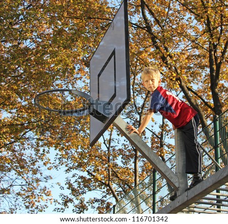 8-year old boy climbing up on a basketball stand