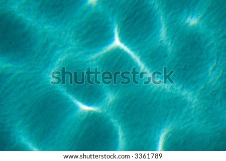 Aqua water with sunlight ripple over sand