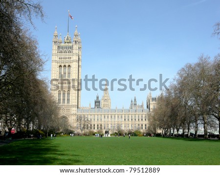 Side view on the British Parliament with a large meadow with green grass in front of it.