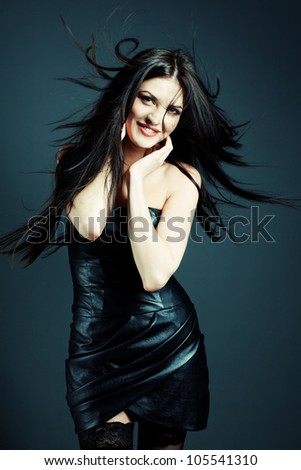 Fashion shot of a beautiful sexy girl in leather fashionable dress in the studio. Hair waving wind