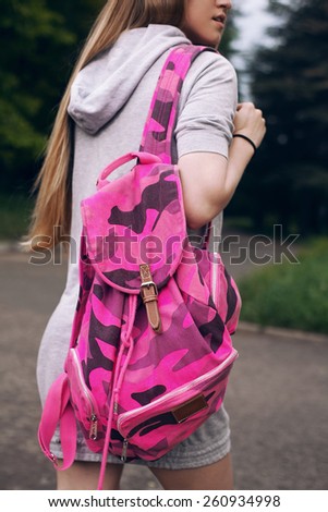 Picture of a slim girl, carrying on her back a bright pink backpack
