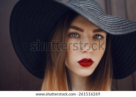 Portrait of a beautiful girl in a black hat with a wide brim and long ombre hairs