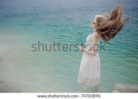 stock photo : Portrait of young beautiful woman in lake in a white dress with flying hair