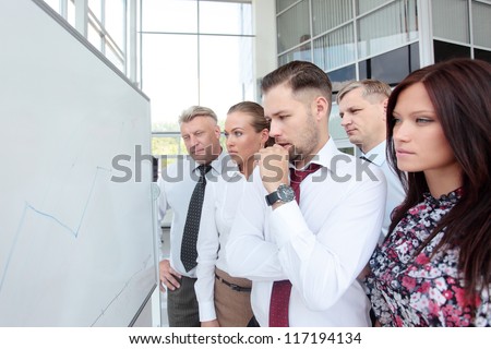 Young man presenting his ideas on whiteboard to colleagues