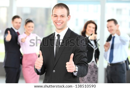 Cheerful business man with team giving you thumbs up