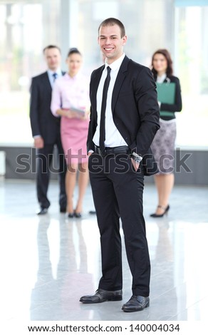 Handsome happy business man with colleagues at the back
