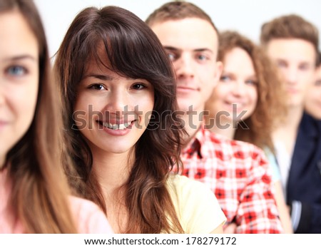 Happy Smiling Students Standing In Row. Young people standing in a row while beautiful young woman standing in front of them and smiling