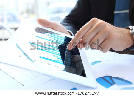 Close-up image of an office worker using a touchpad to analyze statistical data