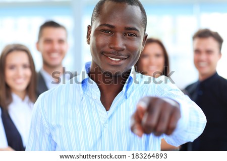 Handsome man pointing his finger at you on the background of business people