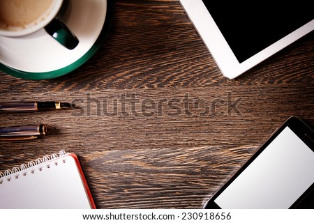 Digital tablet computer with cup of coffee on old wooden desk. Simple workspace or coffee break with web surfing.