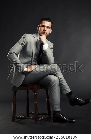Portrait of a handsome man sitting in the armchair over black background.