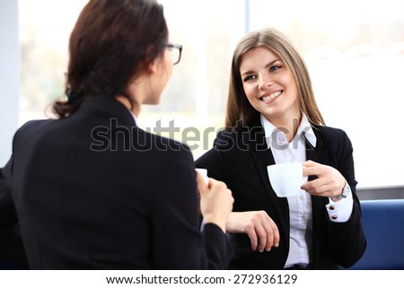 Office workers on coffee break, woman enjoying chatting to colleagues, smiling.