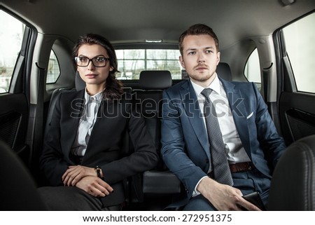 businessman and businesswoman sitting in a limousine. Young businesswoman and businessman in back seat of car