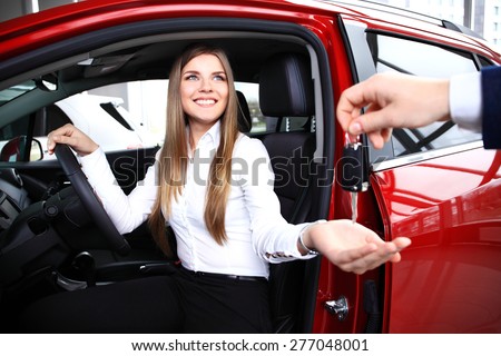 Young woman receiving the keys of her new car