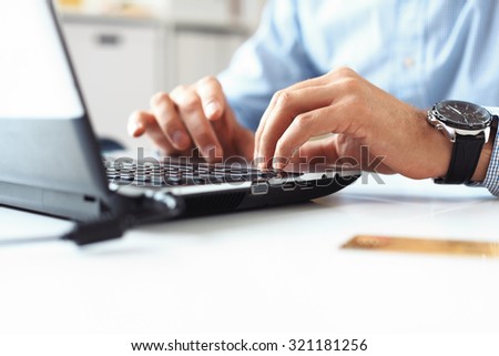 Close-up of male hands typing on laptop keyboard