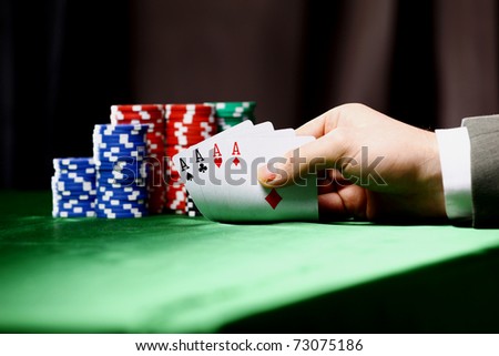 Poker chips and a hand flip the cards isolated against green felt