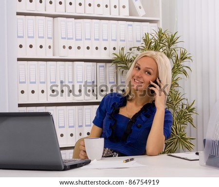 Portrait of a young woman on phone in front of a laptop computer