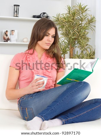 beautiful young woman on the couch with a book