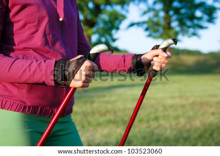 Nordic walking in summer. Closeup of woman's hand holding nordic walking poles