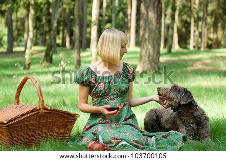 Young woman having a picnic in the wood with a dog