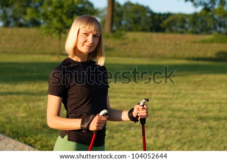 Nordic walking in summer. Young woman walks in the park