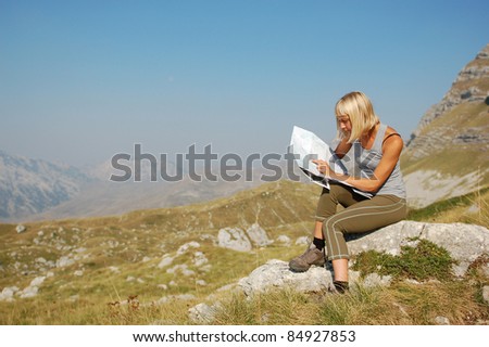 Hiker Woman reading map/A young adult woman studying a map while hiking.