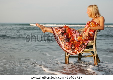 Pretty young woman on the chair/Pretty young woman sitting on the chair sourrounded by the sea