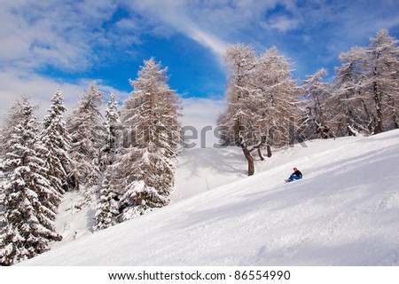 Woman snowboarder relaxing/Young snowboarder sitting  on snow with beautiful winter landscape in the background